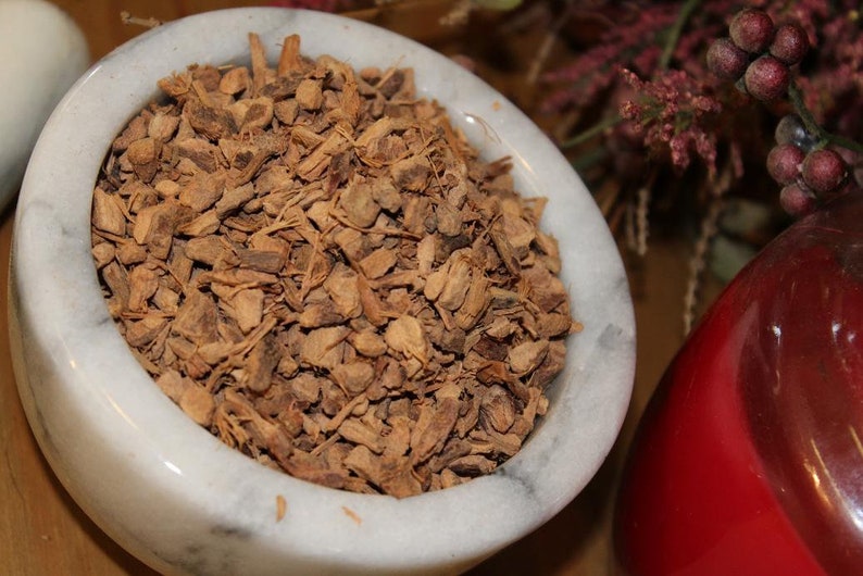 May include: A white marble mortar and pestle filled with dried, brown, chopped root bark.