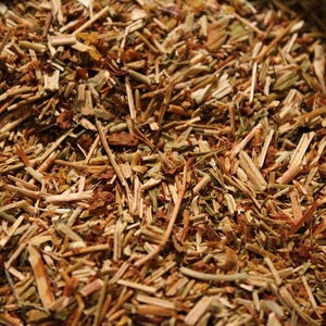May include: Close-up of a bowl filled with dried herbs and flowers. The herbs are a mix of brown, tan, and green, with some yellow flowers mixed in.