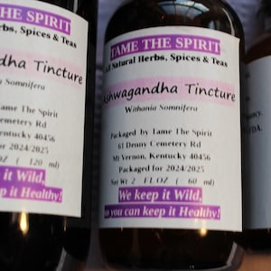 May include: Three glass bottles with brown liquid and white labels. The labels read "Tame The Spirit" and "Ashwagandha Tincture". The bottles are labeled with the ingredients, packaging information, and the text "We keep it wild, so you can keep it healthy!"