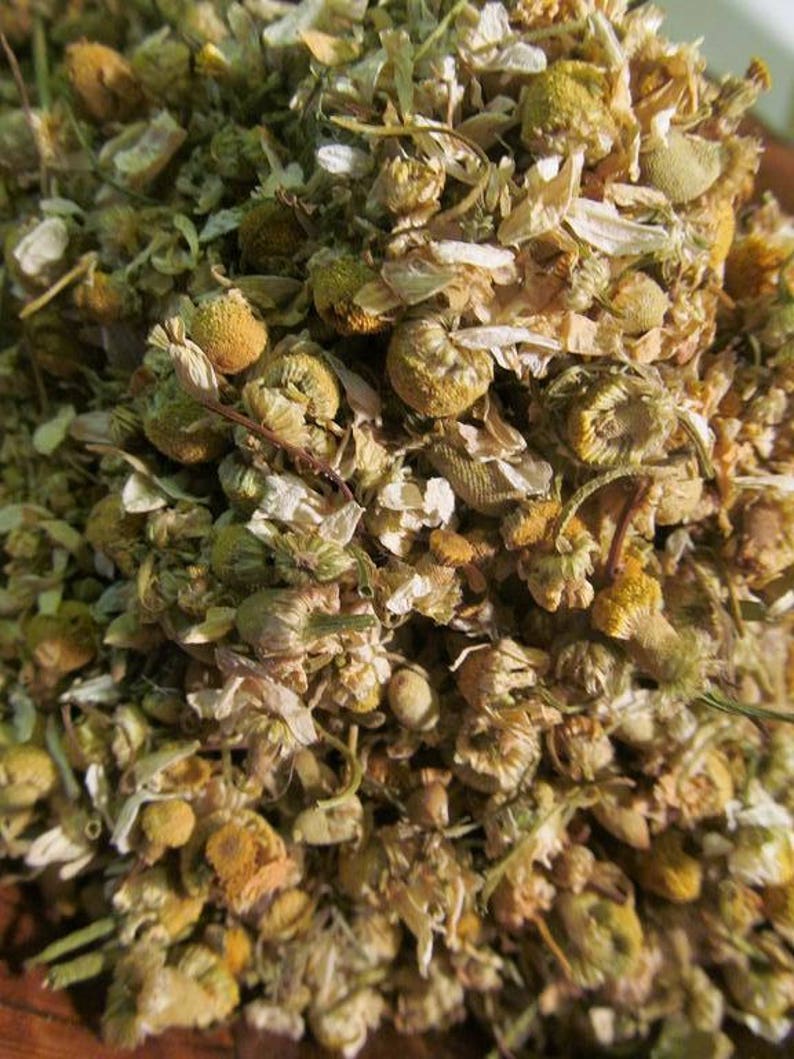 May include: Dried chamomile flowers, a pale yellow and green herbal tea blend. The flowers are dried and ready to be brewed for a relaxing beverage.