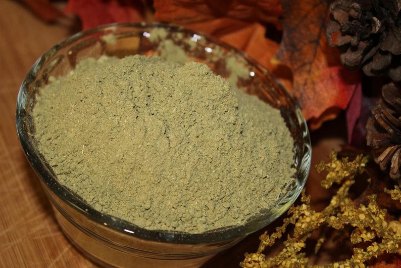 May include: A glass bowl filled with a light green powder. The powder is finely ground and has a uniform texture.