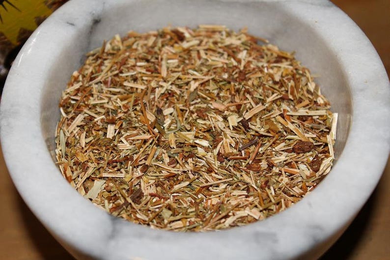 May include: A white ceramic bowl filled with dried herbs, including brown, green, and yellow pieces.