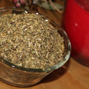 May include: A glass bowl filled with dried green herbs. The herbs are finely chopped and appear to be a blend of different types.