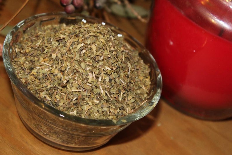 May include: A glass bowl filled with dried green herbs. The herbs are finely chopped and appear to be a blend of different types.