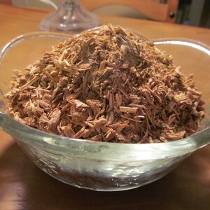 May include: A glass bowl filled with a large amount of light brown wood shavings.