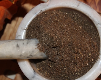 May include: A white marble mortar and pestle with brown powder inside. The mortar and pestle are used for grinding spices, herbs, and other ingredients.