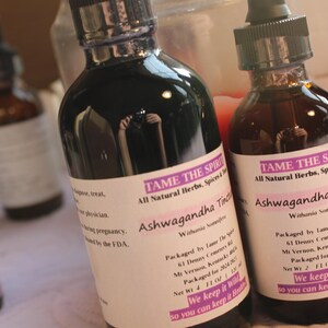 May include: Four glass bottles with dark liquid inside. The bottles are labeled "Tame the Spirit" and "Ashwagandha Tincture". The bottles are all natural herbs, spices, and tinctures. The bottles are packaged in Vermont, USA.