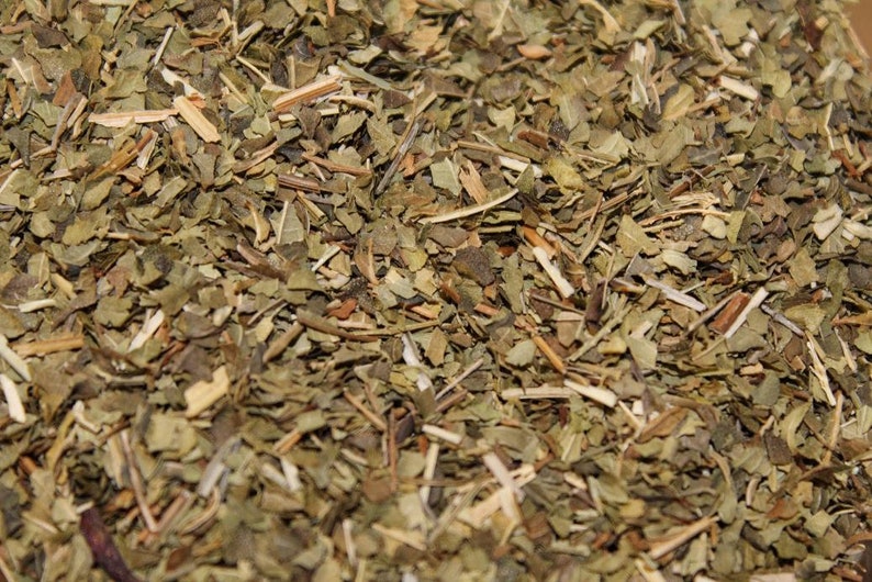 May include: Close-up of dried green and brown herbs, likely a blend for tea or cooking.