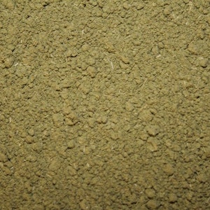 May include: Close-up of a pile of finely ground green powder. The powder has a slightly rough texture and is evenly distributed.