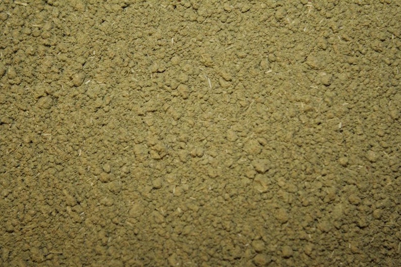 May include: Close-up of a pile of finely ground green powder. The powder has a slightly rough texture and is evenly distributed.