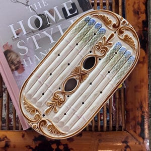 May include: A white ceramic mug with a black handle and the text "But First, Coffee" in a handwritten style. The mug is on a white surface. The mug is approximately 4 inches tall.