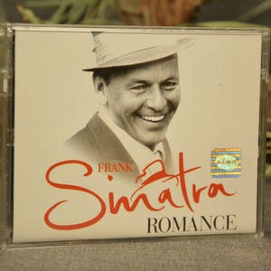 Puede incluir: Una caja de CD con una foto de Frank Sinatra con un sombrero. El texto en la caja dice "FRANK SINATRA ROMANCE".