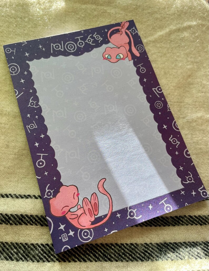Puede incluir: Bloc de notas rectangular con borde morado e interior morado claro. El borde presenta un borde festoneado y s&iacute;mbolos blancos. Se representan dos criaturas de dibujos animados rosas, una en la parte superior y otra en la inferior.