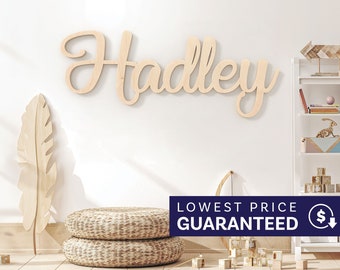 May include: A large, light-colored wooden wall sign featuring the name Hadley in a cursive script font. The letters are connected and have a smooth, natural wood grain finish, mounted horizontally on a plain, light-colored wall surface.