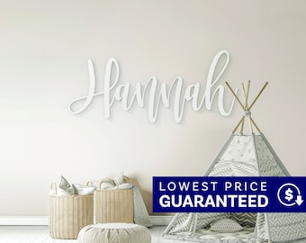 May include: A white wall-mounted sign featuring the name Hannah in a cursive script font. The sign is displayed above a gray and white star-patterned teepee tent and two woven wicker baskets, creating a decorative arrangement for a room.