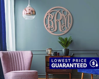 May include: A circular wall-mounted monogram sign featuring the letters BRM in a decorative, interconnected script font. The sign has a metallic rose gold finish and is displayed on a solid wall surface, showcasing intricate, swirling letter designs.