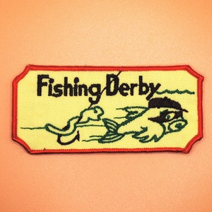May include: Yellow and red embroidered patch with the text "Fishing Derby" and a cartoon fish with a hook in its mouth.