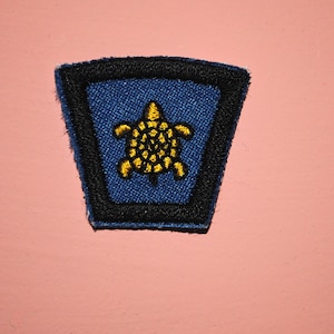 May include: A blue and black embroidered patch with a yellow turtle design.