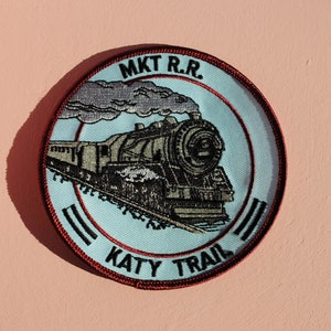 May include: A blue and red embroidered patch with a steam locomotive and the text "MKT R.R. KATY TRAIL".