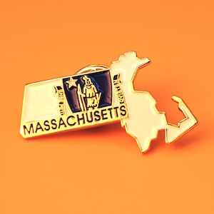 May include: Gold-colored metal pin shaped like the state of Massachusetts with the state flag and the word "MASSACHUSETTS" on the pin.
