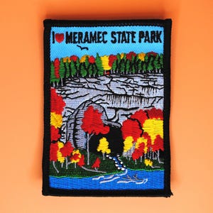 May include: Embroidered patch featuring a scenic view of Meramec State Park. The patch has a blue sky background with the text "I ❤️ Meramec State Park". The design includes a river, trees in fall colors, and a black border.