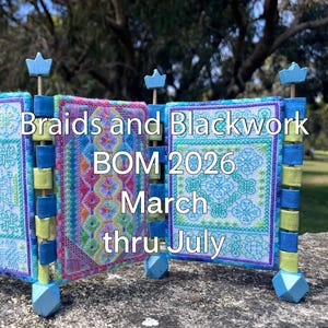 以下が含まれることがあります： 「Braids and Blackwork BOM 2026 March thru July」のテキストが入った、カラフルな手作りのテキスタイルディスプレイ。ピンク、青、緑、紫の色合いで複雑な刺繍が施され、青と緑の木製の支柱で支えられています。