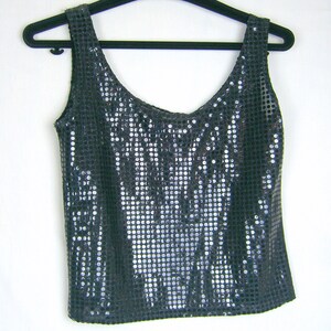 May include: A sleeveless black tank top with silver sequins. The sequins are arranged in a vertical pattern.