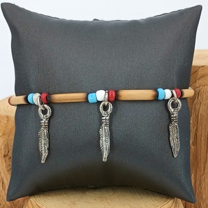 May include: A wooden bracelet with red, white, and blue beads and three silver feather charms.