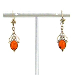 May include: A pair of silver dangle earrings with orange amber stones. The earrings have a delicate, ornate design.