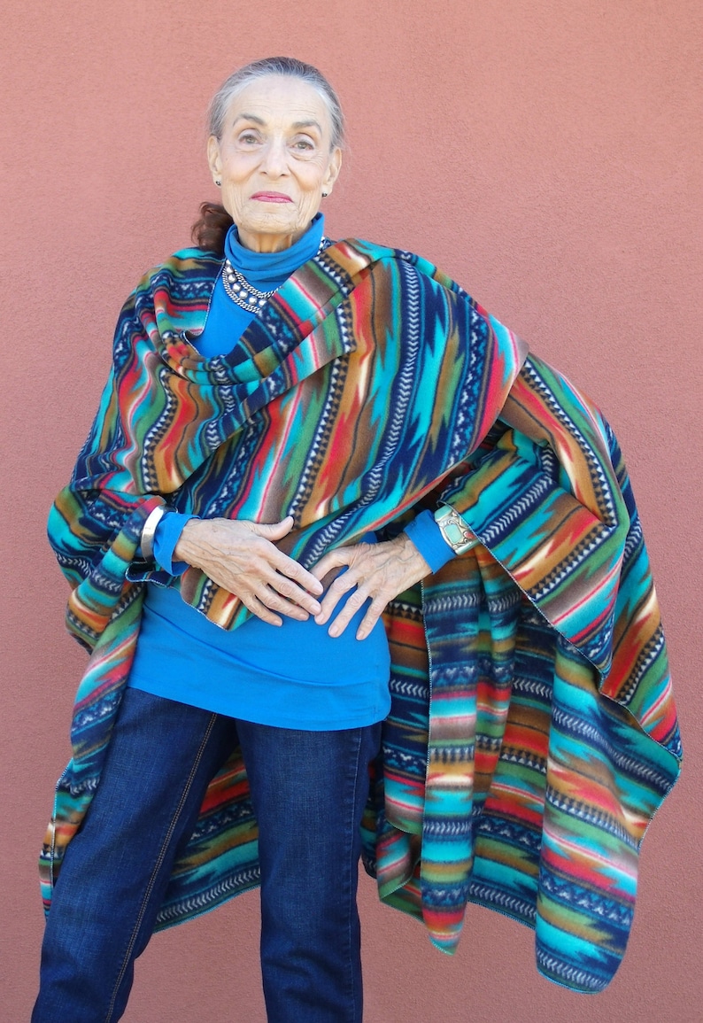 May include: A woman wearing a colorful striped poncho with a blue shirt and jeans.