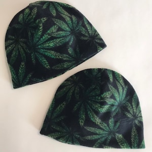 May include: Two black fleece beanies with a green marijuana leaf pattern.