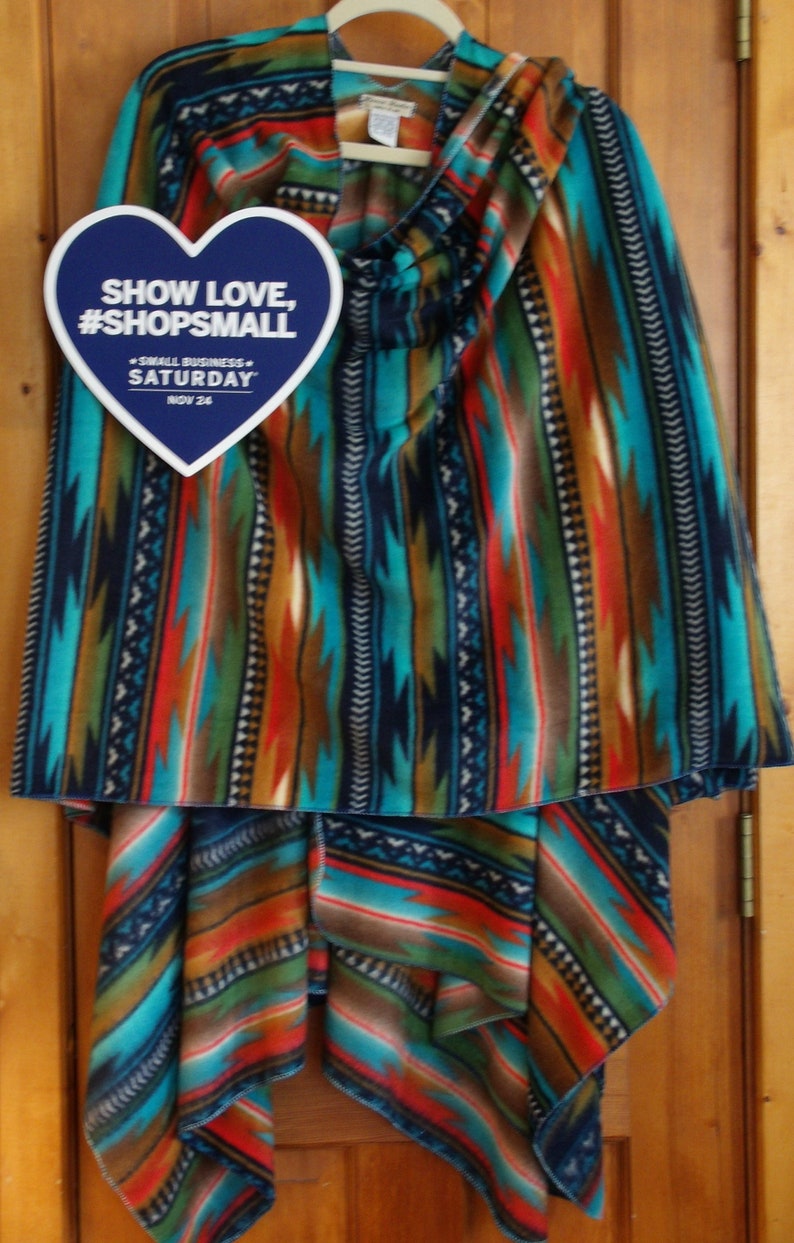 May include: A blue, red, orange, and turquoise patterned fleece blanket with a heart-shaped tag that says "Show Love, #ShopSmall - Small Business - Saturday, Nov 24".
