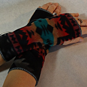 May include: A pair of black fingerless gloves with a colorful southwestern pattern. The gloves are made of a soft, warm fabric and have a black trim.