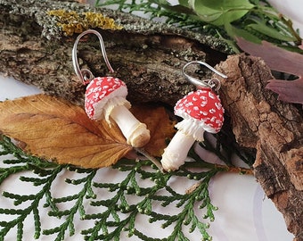 Op de afbeelding: Een paar rode en witte paddenstoel oorbellen met zilveren haakjes. De paddenstoelen zijn gemaakt van polymer clay en hebben een realistische uitstraling.