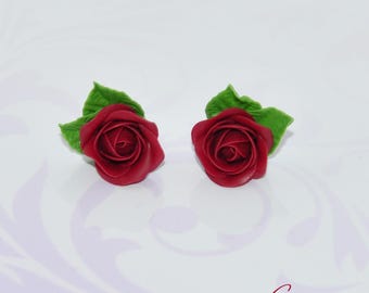 May include: A pair of red rose earrings with green leaves. The roses are made of polymer clay and are hand-crafted.