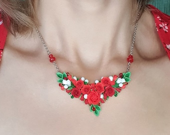 Könnte beinhalten: Eine silberne Halskette mit einem roten und weißen Blumendesign. Die Halskette ist aus Polymer Clay gefertigt und zeigt eine Ansammlung von roten Rosen und weißen Blüten.