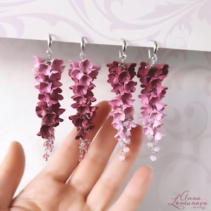 May include: Four pairs of dangle earrings with a gradient of pink and burgundy flowers. The earrings are made of polymer clay and have silver hooks.