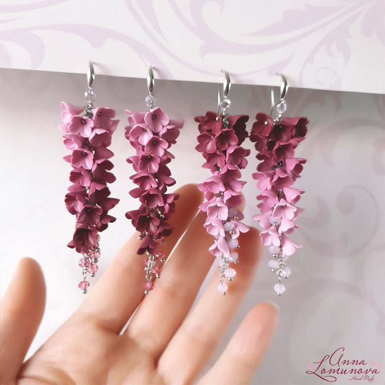 May include: Four pairs of dangle earrings with a gradient of pink and burgundy flowers. The earrings are made of polymer clay and have silver hooks.