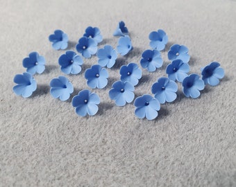 May include: A collection of 18 light blue felt flower embellishments. The flowers are all the same size and shape, with five petals and a small hole in the centre.