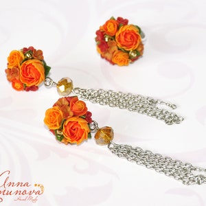 Peut inclure: Une paire de boucles d'oreilles en forme de fleurs orange et jaunes avec une cha&icirc;ne pendante. Les boucles d'oreilles sont faites &agrave; la main et comportent une petite perle de cristal.