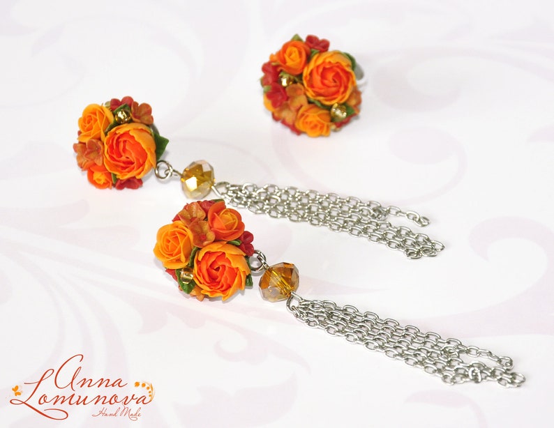 Peut inclure: Une paire de boucles d'oreilles en forme de fleurs orange et jaunes avec une cha&icirc;ne pendante. Les boucles d'oreilles sont faites &agrave; la main et comportent une petite perle de cristal.
