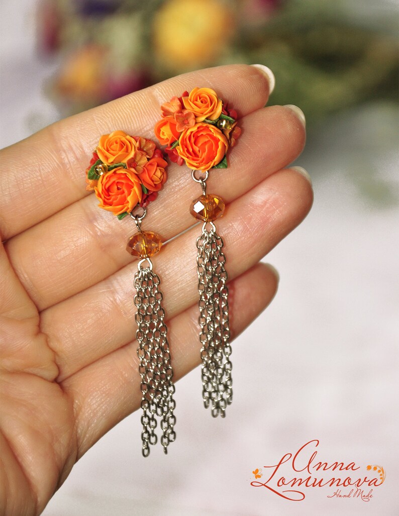 Peut inclure: Boucles d'oreilles en forme de fleurs orange et rouge avec des cha&icirc;nes argent&eacute;es et des perles de cristal transparentes.