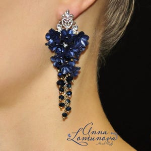 May include: Long, dangling earrings with a silver crown-shaped top and a cascade of dark blue fabric flowers and black crystal beads.
