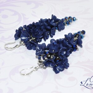 May include: A pair of dangle earrings featuring clusters of dark blue polymer clay flowers with silver accents and dark blue glass beads.