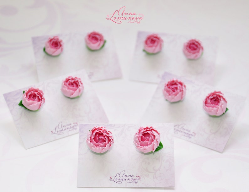 Pode incluir: Brincos de flores cor-de-rosa em cart&otilde;es brancos com o texto "Anna Lamunova" em cada cart&atilde;o.