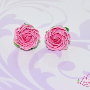 Pode incluir: Um par de brincos de argila polim&eacute;rica rosa em forma de rosas. Os brincos s&atilde;o feitos &agrave; m&atilde;o e t&ecirc;m um visual delicado e feminino.