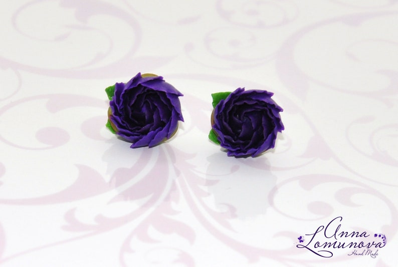 May include: A pair of purple polymer clay earrings shaped like roses with green leaves.