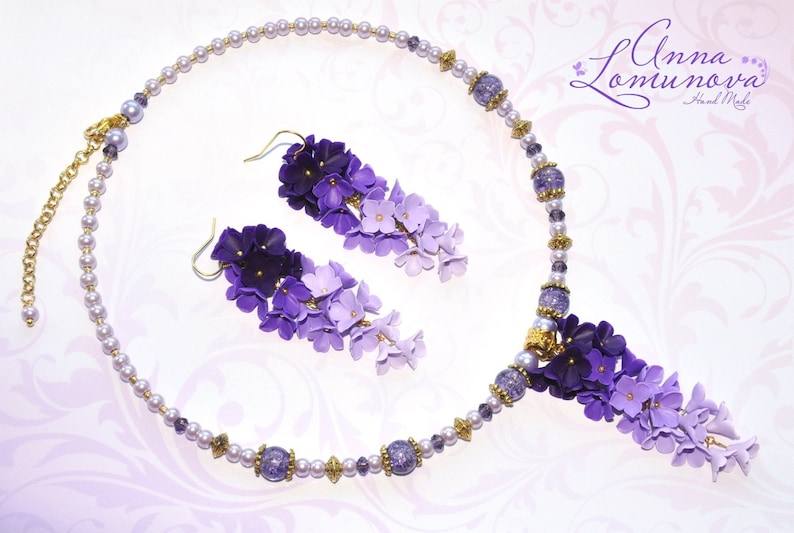 Peut inclure: Un collier et des boucles d'oreilles assortis en fleurs violettes et lavande. Le collier est compos&eacute; de petites perles nacr&eacute;es et d'un pendentif de fleurs en cascade. Les boucles d'oreilles sont &eacute;galement compos&eacute;es de fleurs en cascade.