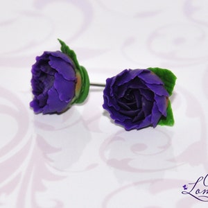 May include: A pair of purple flower earrings with green leaves. The earrings are made of polymer clay and are handmade.