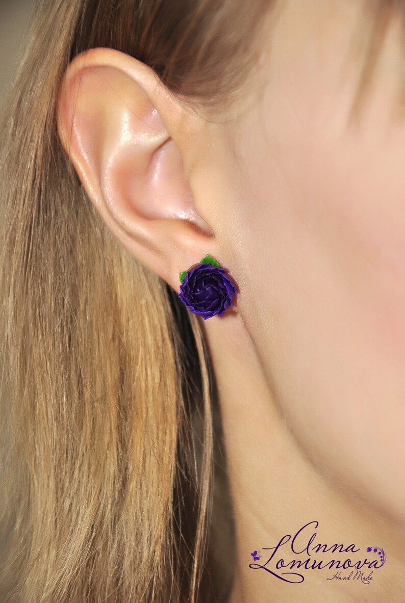 May include: Purple flower stud earrings with green leaves. The earrings are handmade and feature a delicate, realistic design.